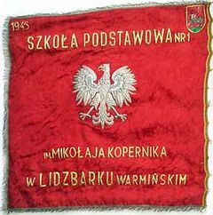 Sztandar szkoły, źródło: Szkoła Podstawowa nr 1 im. Mikołaja Kopernika w Lidzbarku Warmińskim, 5.12.2013.